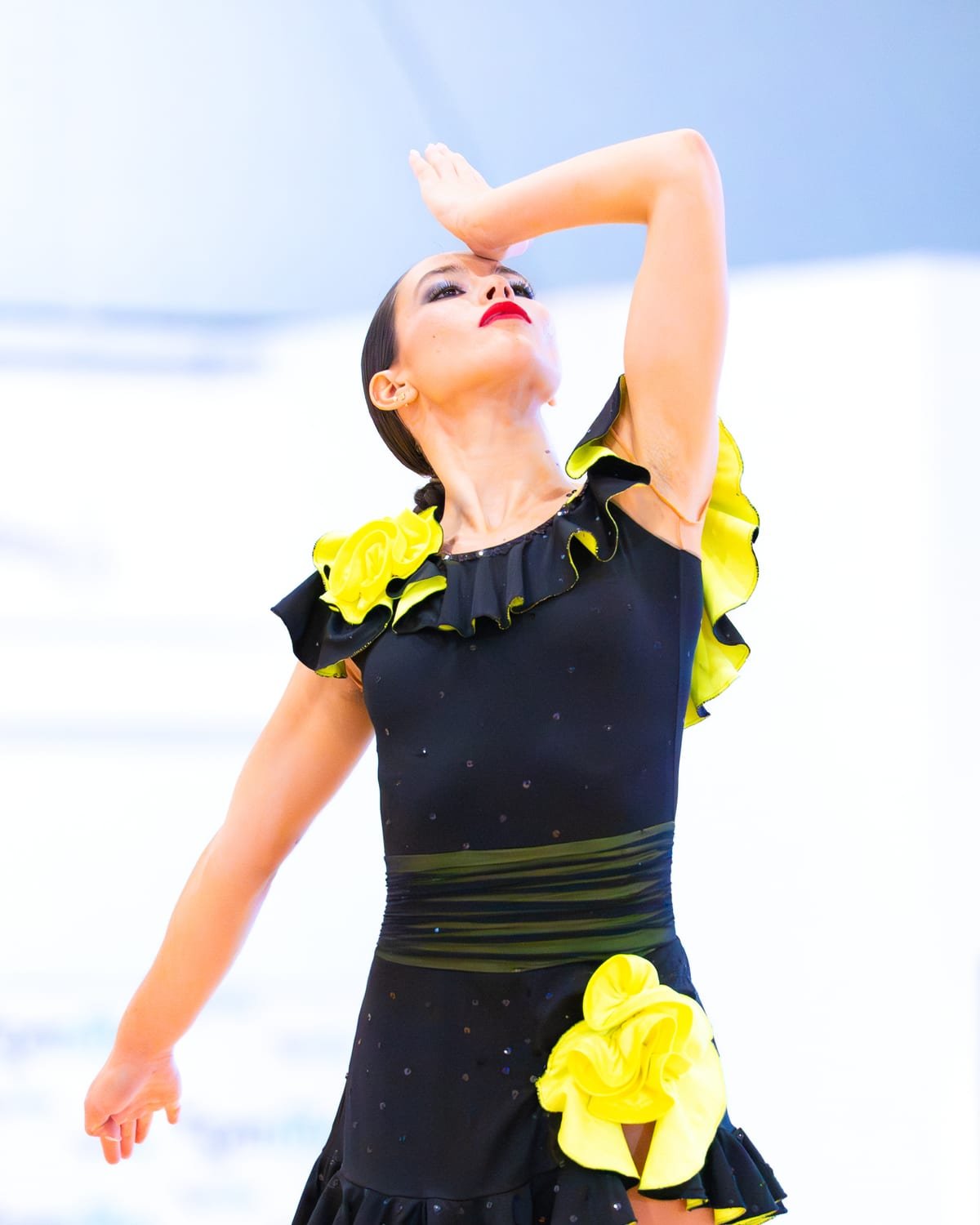 Patinadora con vestido negro y volantes amarillos, en tensión durante su ejercicio de competición — foto de Pablo González