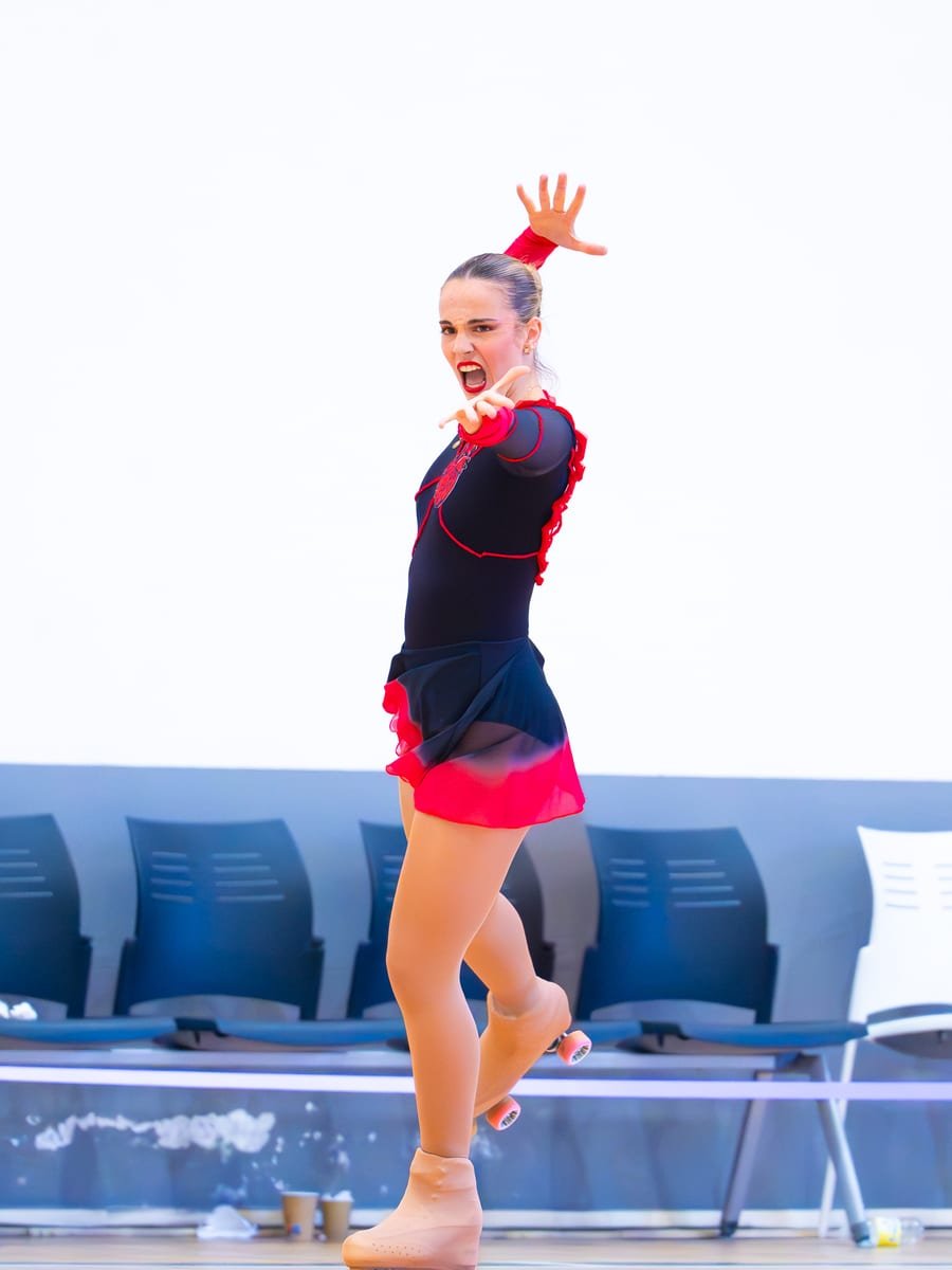 Patinadora con vestido rojo y negro en una pose dramática de competición — foto de Pablo González
