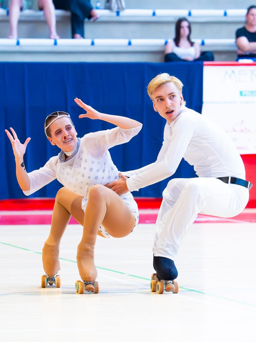 Pareja de patinaje artístico sincronizada en una figura baja sobre la pista — foto de Pablo González